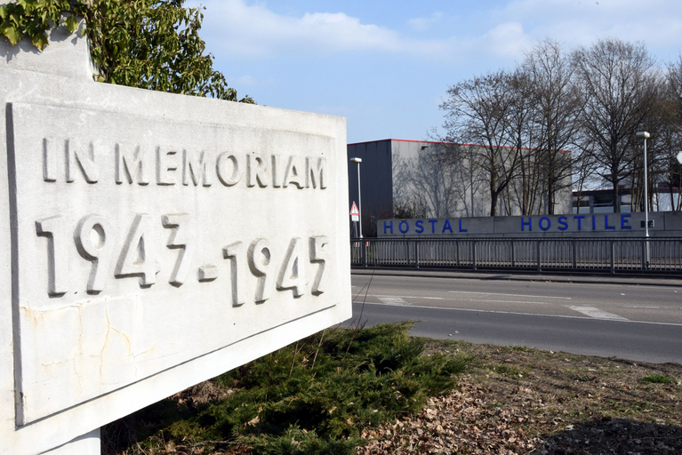 Zwei Gedenkstätten, ein Ort: Im Vordergrund der Obelisk als Zeugnis der Gedenkstätte von 1947. Im Hintergrund die Vorderseite der 2004 als "Hotel der Erinnerung" neugestalteten Gedenkstätte Gestapo-Lager Neue Bremm. Foto: Zentrum für Medien/Bildungscampus des Saarlandes/Mechthild Schneider (2010)